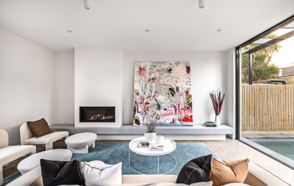 Spacious living room with built-in fireplace and floor to ceiling window overlooking the pool at the Sandringham townhouses.